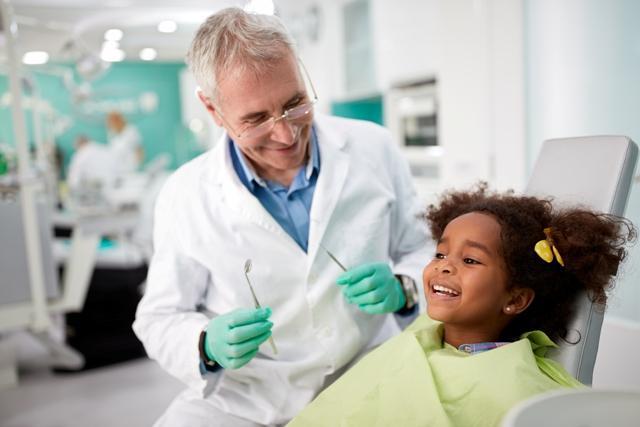 Male dentist with smiling child patient