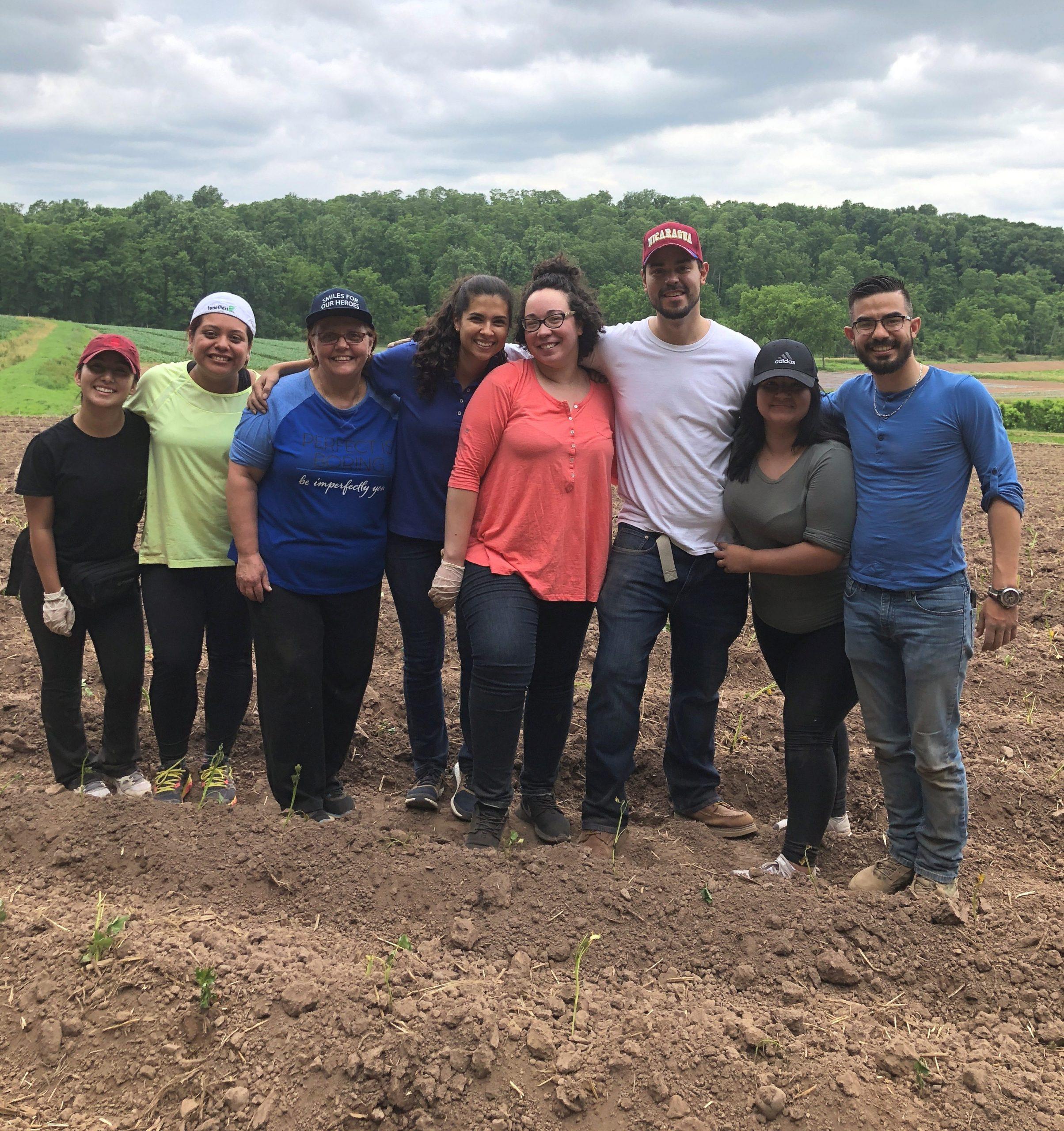 Eight members of Zufall's Outreach staff standing next to sweet potato plants they planted.