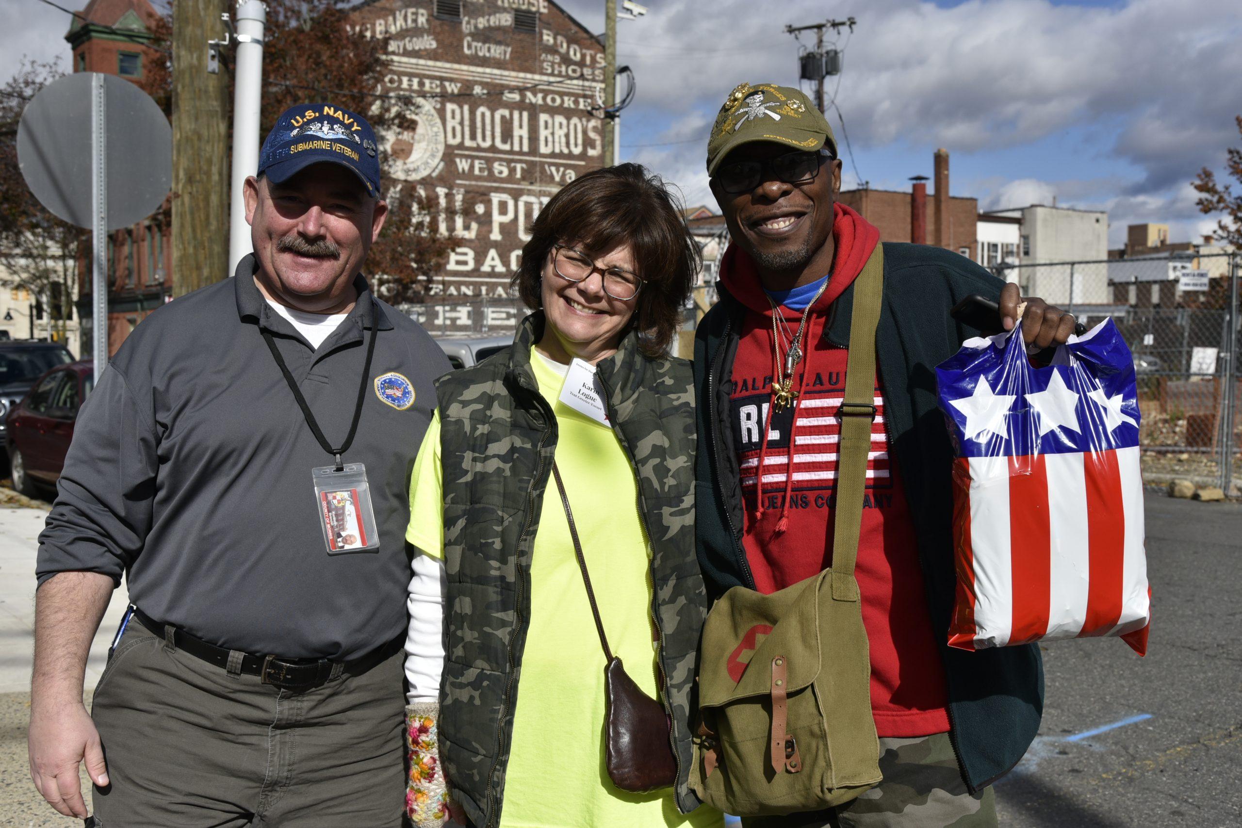 A volunteer at the Smiles for Our Heroes events poses with two veterans.