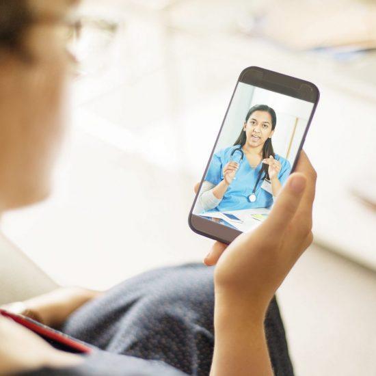 Photo of a Telemedicine Patient speaking with a medical Provider on Cell Phone. The provider is wearing blue scrubs.
