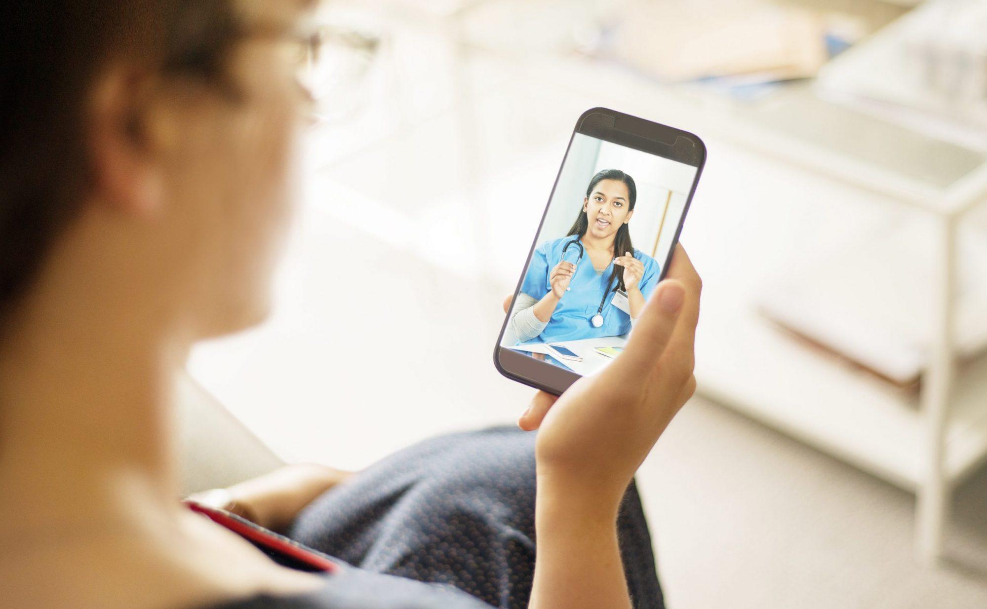 Photo of a Telemedicine Patient speaking with a medical Provider on Cell Phone. The provider is wearing blue scrubs.