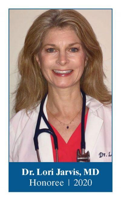 Headshot of Dr. Loris Jarvis. Dr. stares straight and smiles. She has long dark blond hair and wears a red shirt, white lab coat and a stethoscope around her neck.
