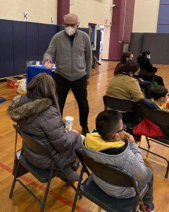 Man with mask responding to woman seated next to her child