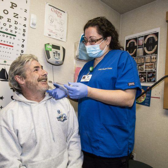 Man receives a dental cleaning from a dental provider wearing a mask