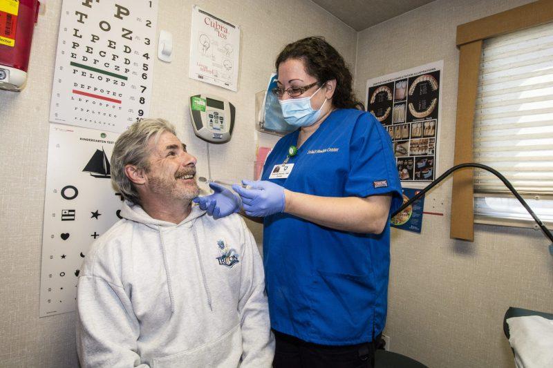 Man receives a dental cleaning from a dental provider wearing a mask