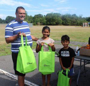 a man and two children holding grocery bags outside
