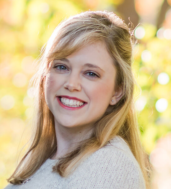 Professional headshot of a woman smiling in front of yellow leaves