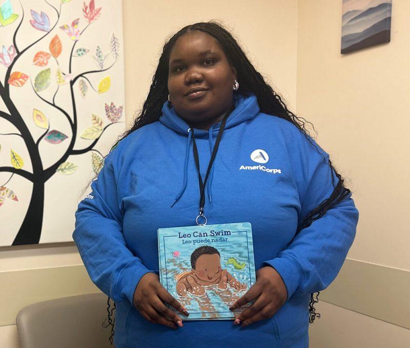 Person in blue sweatshirt holding book